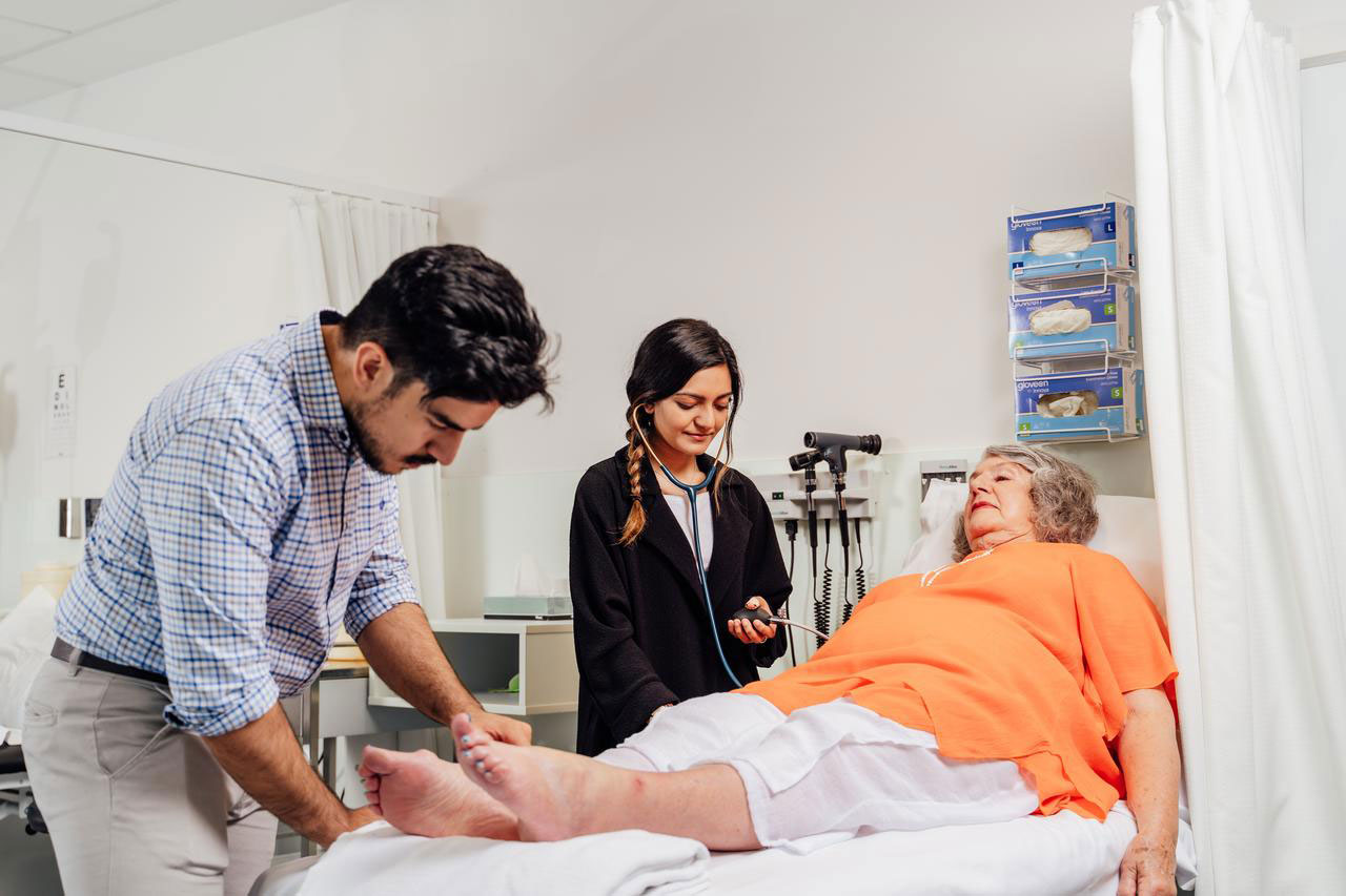 Paramedicine students assessing patient in hospital bed